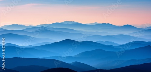 A series of layered mountain ranges fading into the distance under a gradient sunset sky  each layer a deeper shade of blue.