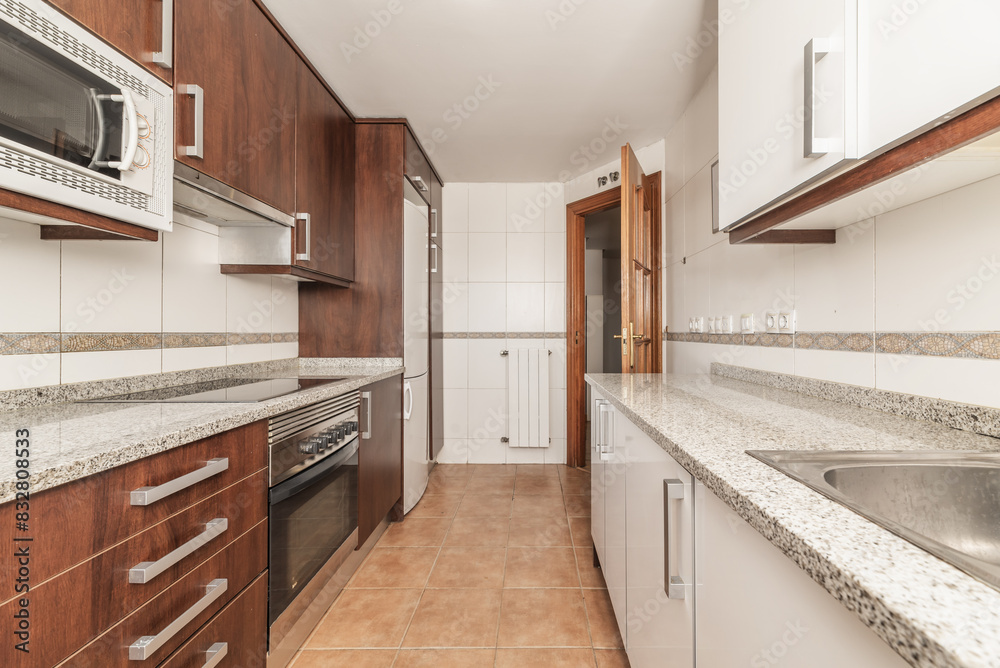 A kitchen with brown wooden furniture, with integrated appliances, and light brown stoneware floors A kitchen with brown wooden furniture, with integrated appliances, and light brown stoneware floors