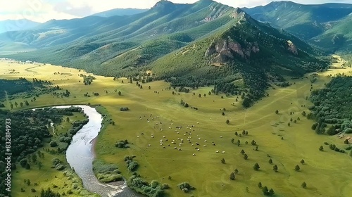   An aerial photo of a valley containing a river and mountain ranges behind it