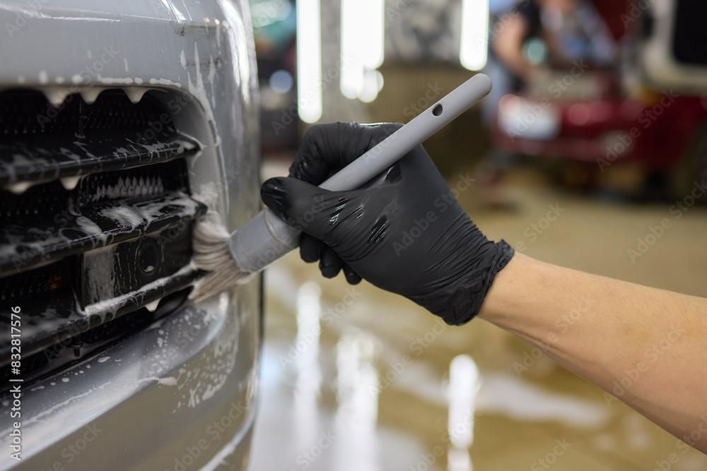 A person is cleaning a car windshield with a brush and water A person is cleaning a car windshield with a brush and water