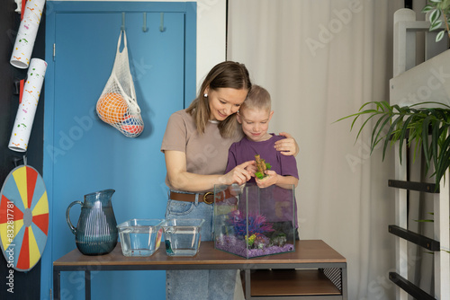 Tender moment of mother and son caring for pet fish photo