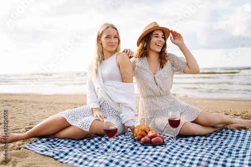 Two women female friends having picnic brunch with wine, sitting near sea. Vacation , relax, hen-party