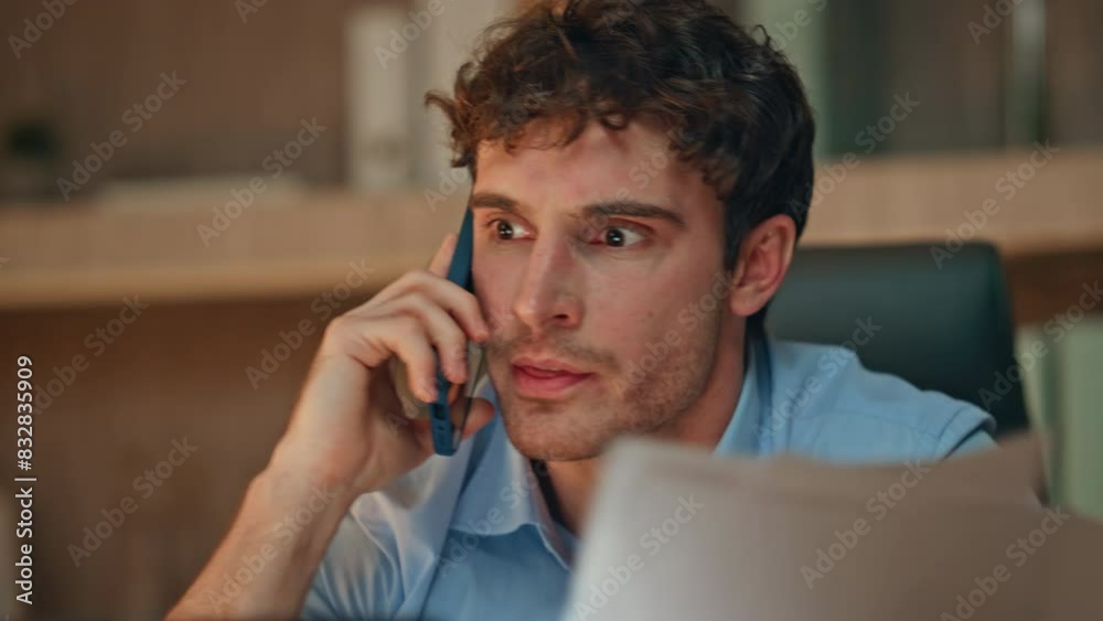 Furious executive shouting mobile phone holding papers in evening room close up. Furious executive shouting mobile phone holding papers in evening room close up.