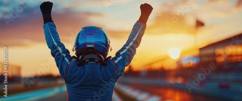 Racing driver celebrating victory in a car race, standing with raised hands on the track at sunset, wearing a blue suit and helmet, back view. Highly detailed, ultra realistic photo photo