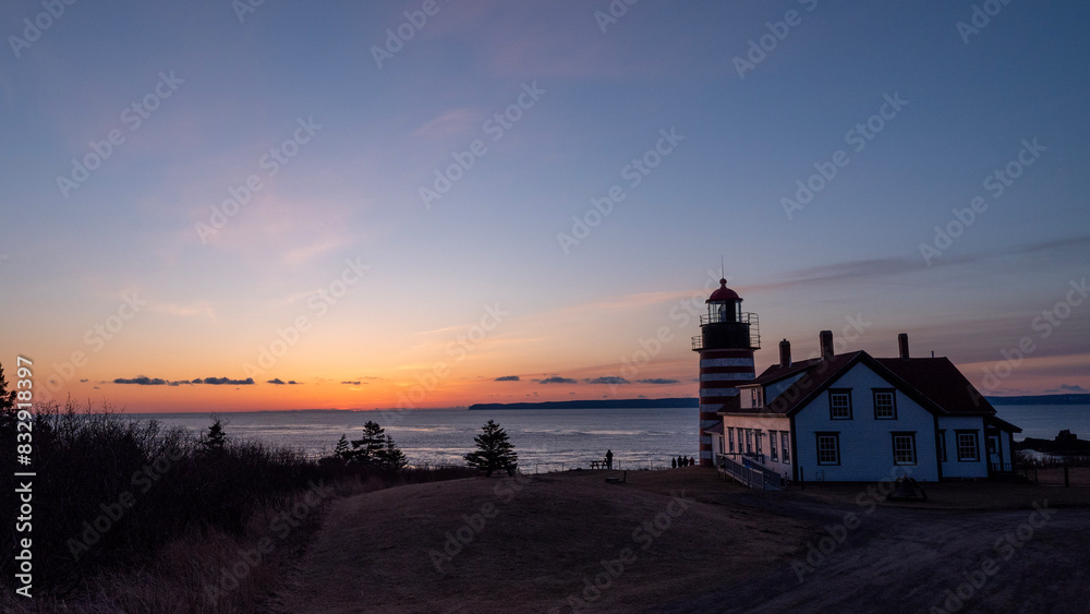 Lighthouse stands at the water surface's edge by a dirt road Lighthouse stands at the water surface's edge by a dirt road