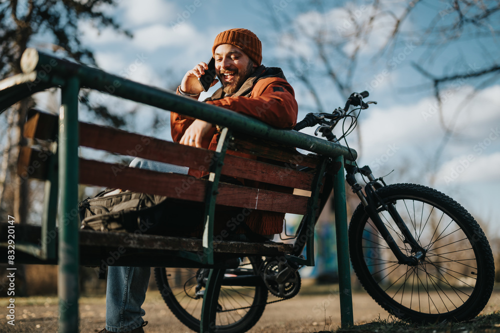 A young man in casual attire enjoying a quiet moment on a park bench beside his mountain bike, embracing the tranquility of nature. A young man in casual attire enjoying a quiet moment on a park bench beside his mountain bike, embracing the tranquility of nature.