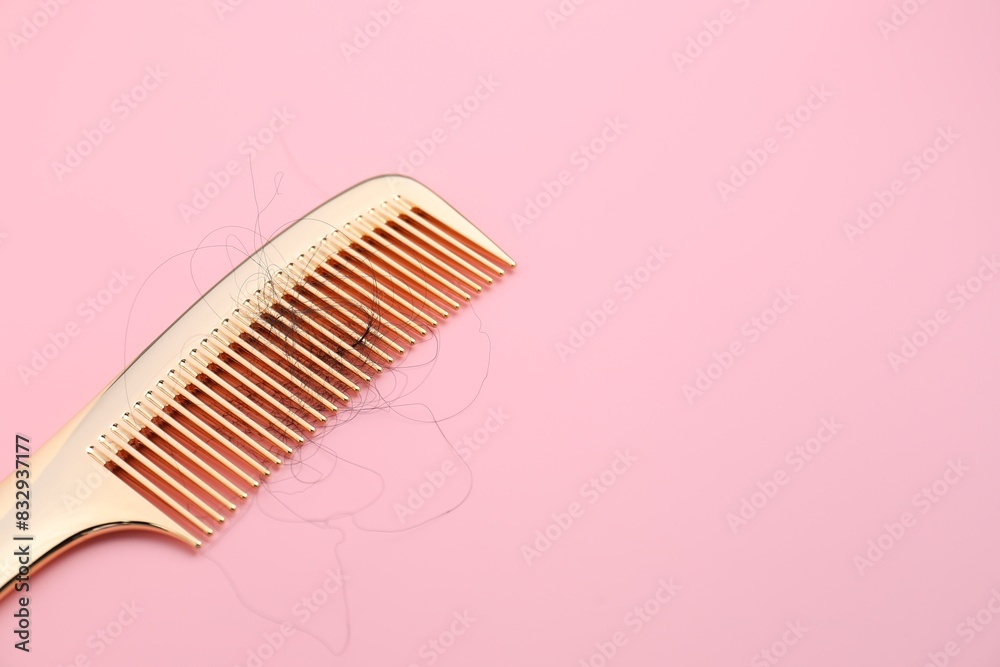 Comb with lost hair on pink background, space for text