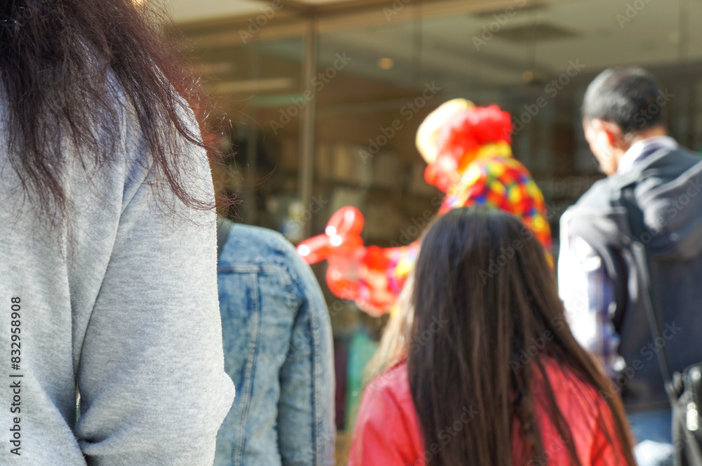 Obraz premium 町中で芸を披露している大道芸人を囲うようにしてできた人だかり