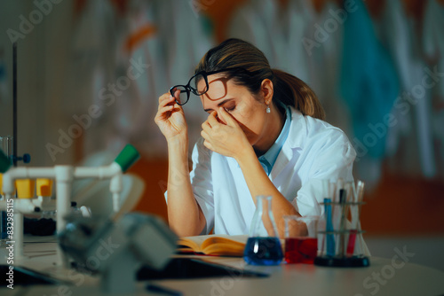 Photos Tired Scientist Rubbing her Eyes Sitting in a Laboratory
