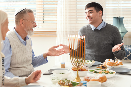 Young man having dinner with his parents at home on Hanukkah