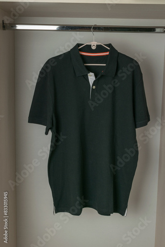 Black Polo Shirt Hanging on a Hanger in a Wardrobe