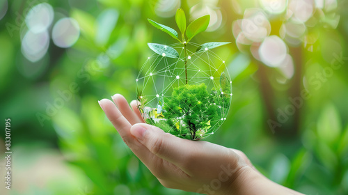 A person is holding a green globe in their hand. The globe is surrounded by green grass and leaves, giving the impression of a natural environment. Concept of harmony between humanity and nature