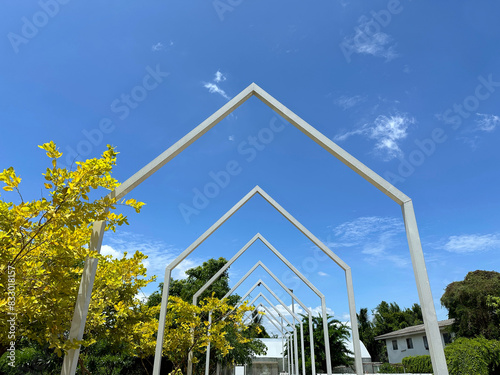 A white gable-shaped steel structure like a house roof creates a walkway design within the garden.