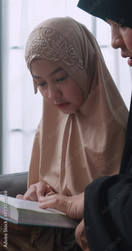 Vertical clip. Muslim girl learns the holy Quran with her mother at home. Vertical clip. Muslim girl learns the holy Quran with her mother at home.