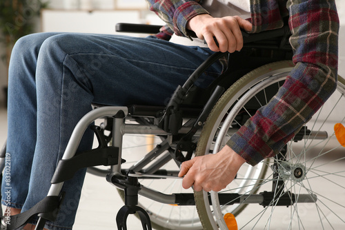 Young man with wrench repairing his wheelchair at home, closeup