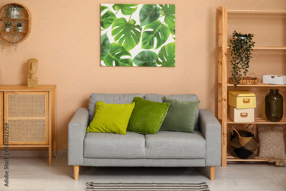 Fototapeta premium Modern living room interior with gray sofa, green pillows, wooden furniture, and monstera leaf wall art