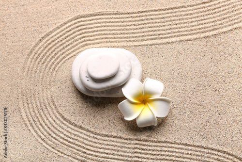 Stones and plumeria on sand with lines