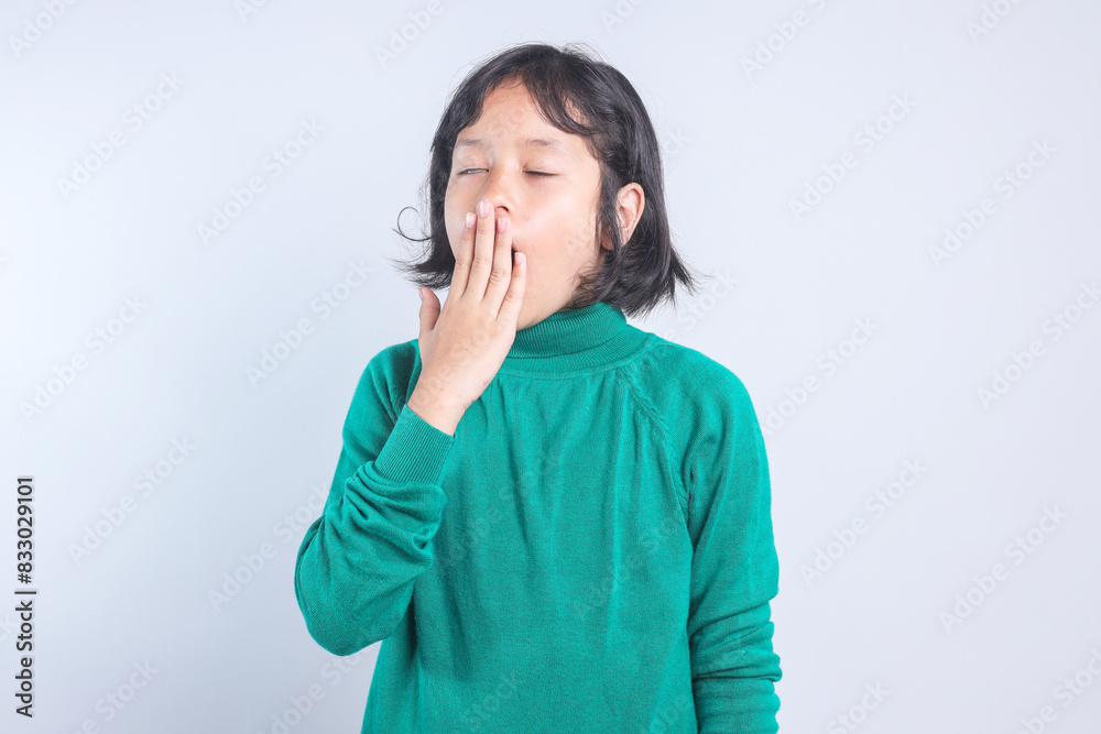 Sleepy child girl yawning while covering her mouth isolated on grey background Sleepy child girl yawning while covering her mouth isolated on grey background