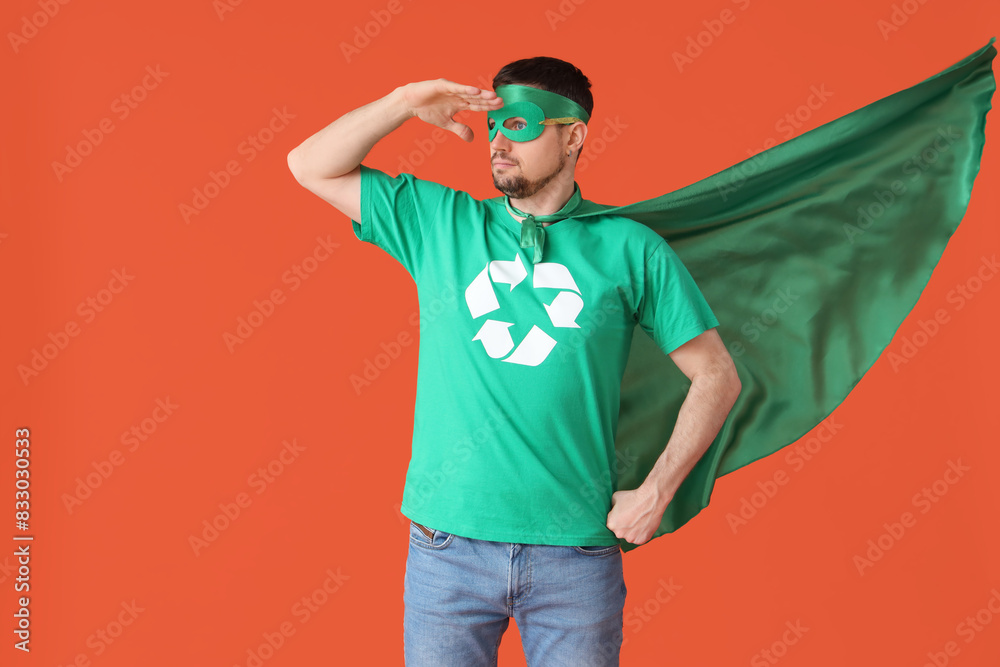 Young man dressed as eco superhero looking at something on orange background. Ecology concept Young man dressed as eco superhero looking at something on orange background. Ecology concept