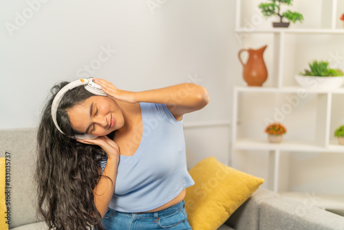 Woman feeling the music dancing sitting on the sofa photo