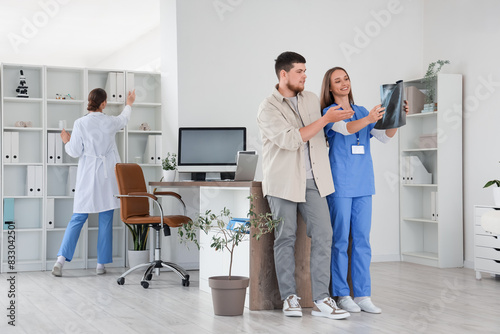 Female doctor showing x-ray image of lungs to young man at hospital photo