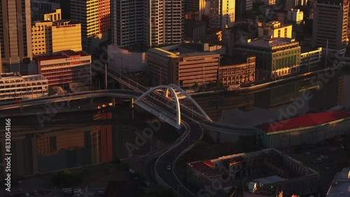 Aerial view of Manila during sunset, highlighting Binondo Intramuros Bridge, vibrant reflections, urban architecture, and the winding river under golden light photo