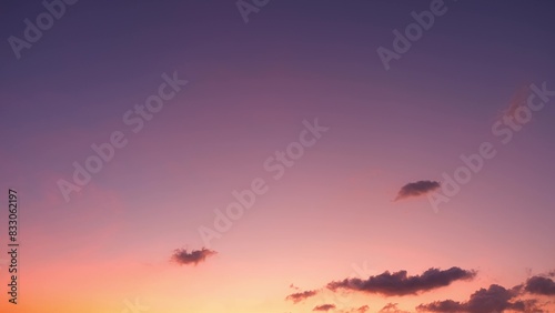 A stunning sunset with a gradient sky transitioning from deep purple at the top to warm pink and orange hues near the horizon. Dark  scattered clouds add depth to the scene. Sunset sky background. 