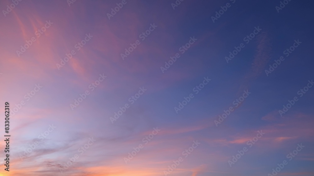 Obraz premium A peaceful sunset with the sky painted in soft shades of pink, purple, and blue. Wispy clouds stretch across the horizon, reflecting the warm colors of the setting sun, creating a tranquil. 