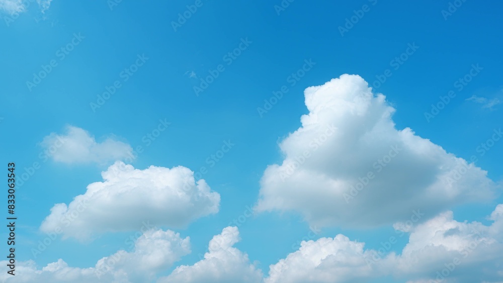 A clear blue sky with a few large, fluffy white clouds floating gently. The clouds are well-defined against the vivid blue background, creating a bright and peaceful scene. Nature background.
A clear blue sky with a few large, fluffy white clouds floating gently. The clouds are well-defined against the vivid blue background, creating a bright and peaceful scene. Nature background.