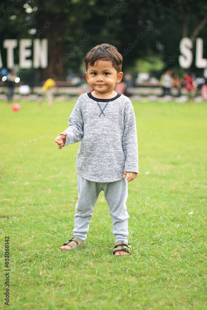 A handsome young boy, nicely dressed showing an expression of joy with hands up in the air looking excited and happy to be playing outdoors. A handsome young boy, nicely dressed showing an expression of joy with hands up in the air looking excited and happy to be playing outdoors.