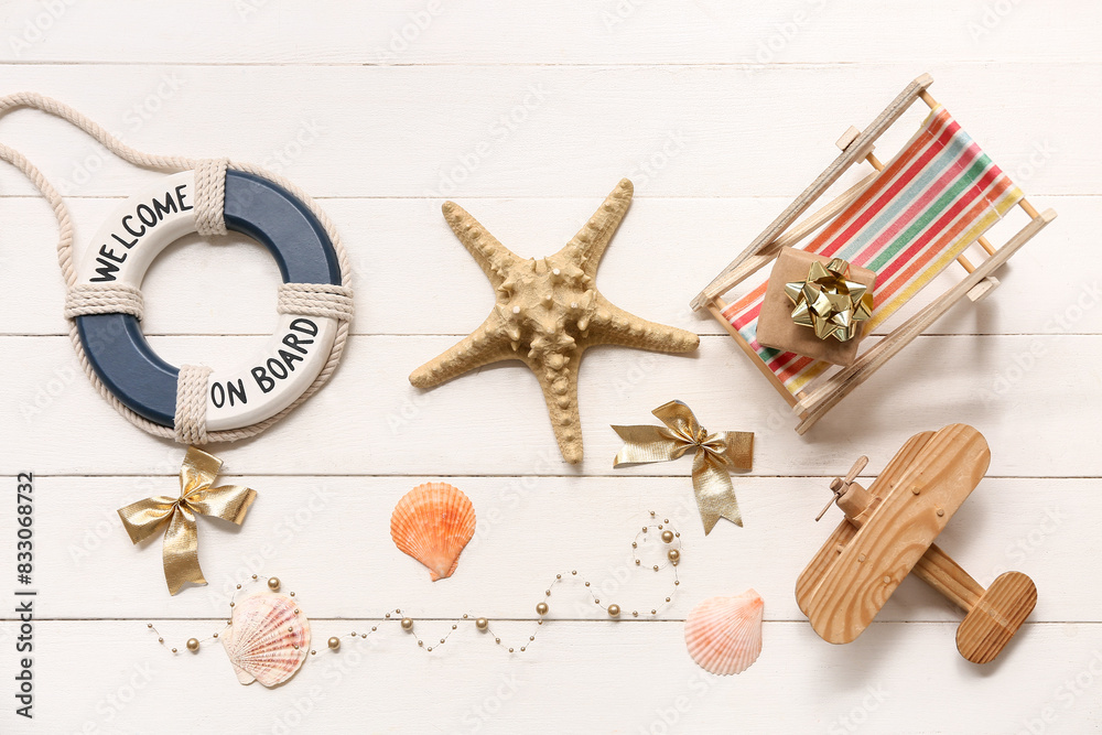 Tiny deck chair, starfish, wooden airplane and lifebuoy on white wooden background. Top view Tiny deck chair, starfish, wooden airplane and lifebuoy on white wooden background. Top view