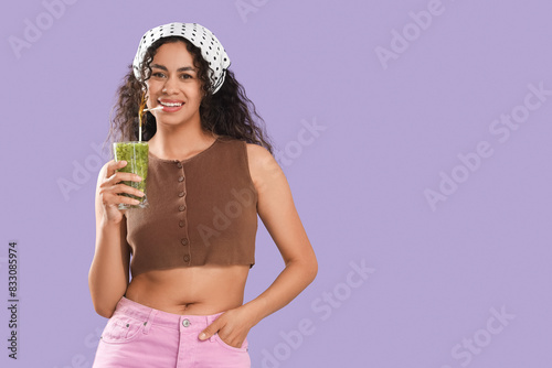 Beautiful young happy African-American woman with glass of tasty kiwi smoothie on purple background © Pixel-Shot