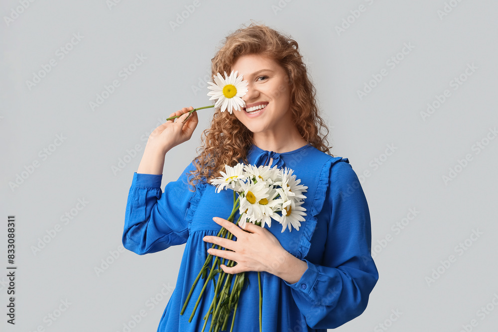 Beautiful young woman with chamomile flowers on grey background Beautiful young woman with chamomile flowers on grey background