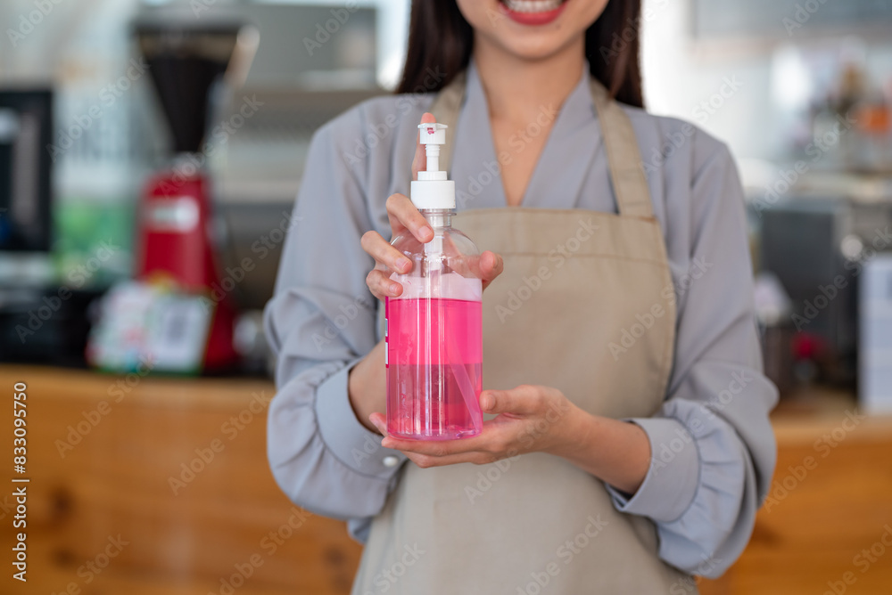 Woman coffee shop employee holds hand sanitizer. Woman coffee shop employee holds hand sanitizer.