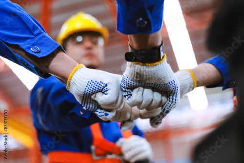 Group of industrial factory workers bumping fists together,showing gesture for teamwork or unity. photo