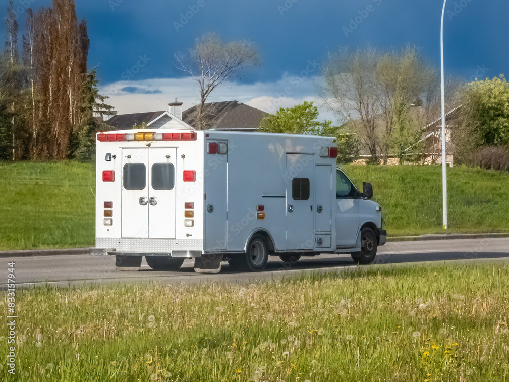 A rear view of a plain white ambulance traveling on the road. A rear view of a plain white ambulance traveling on the road.