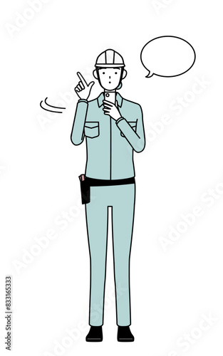 Female engineer in helmet and work wear operating a smartphone.