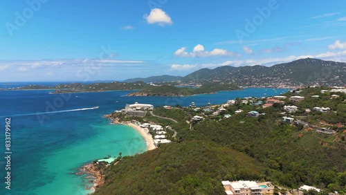 wide rising capture of st. thomas in the virgin islands during a bright summer day from a drone showing many boats, houses, and hotels on the island