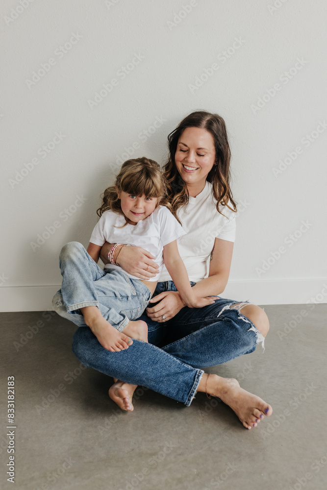 Mother and daughter sit on floor snuggled up together Mother and daughter sit on floor snuggled up together