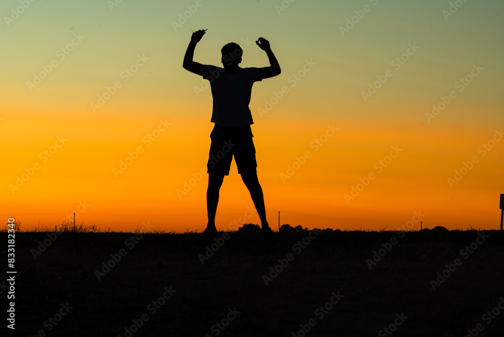 Silhouette of a person jumping against a vibrant sunset sky. Silhouette of a person jumping against a vibrant sunset sky.