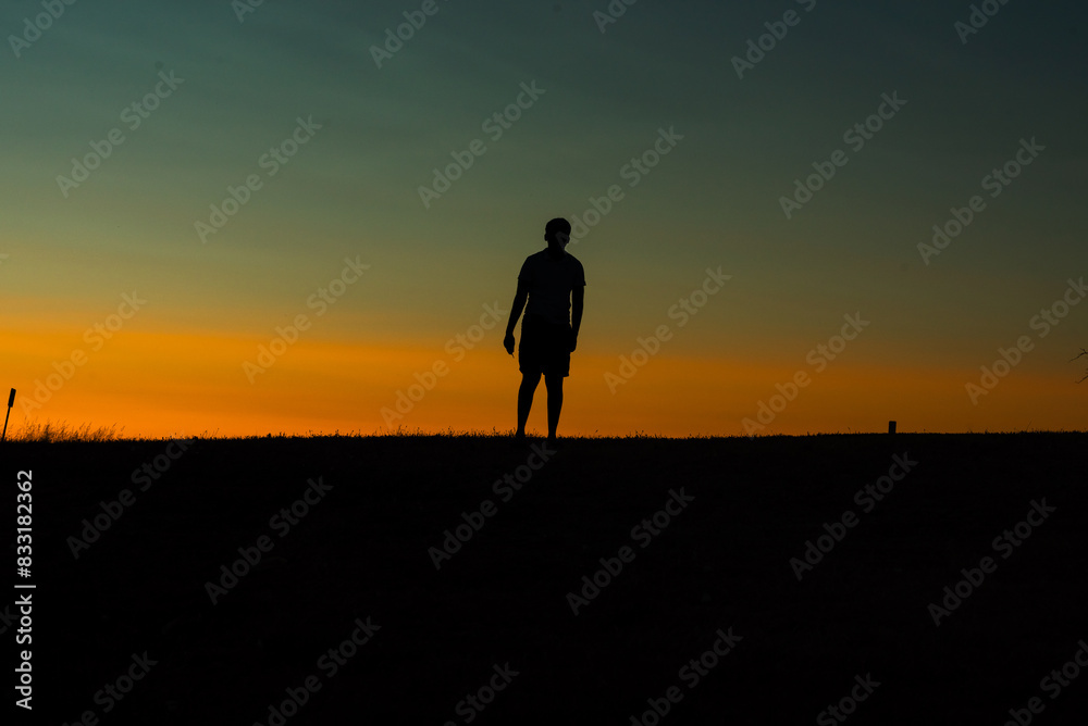 Silhouette of a person standing against a vibrant sunset sky.