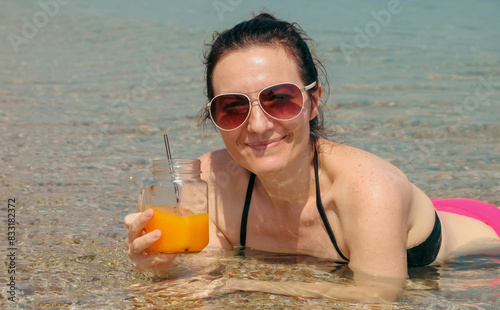 Smiling woman enjoying refreshing drink in the sea