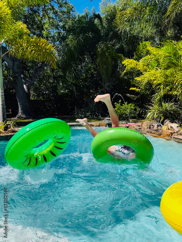 Принти на полотні A boy flips upside down on a green raft in a swimming pool.