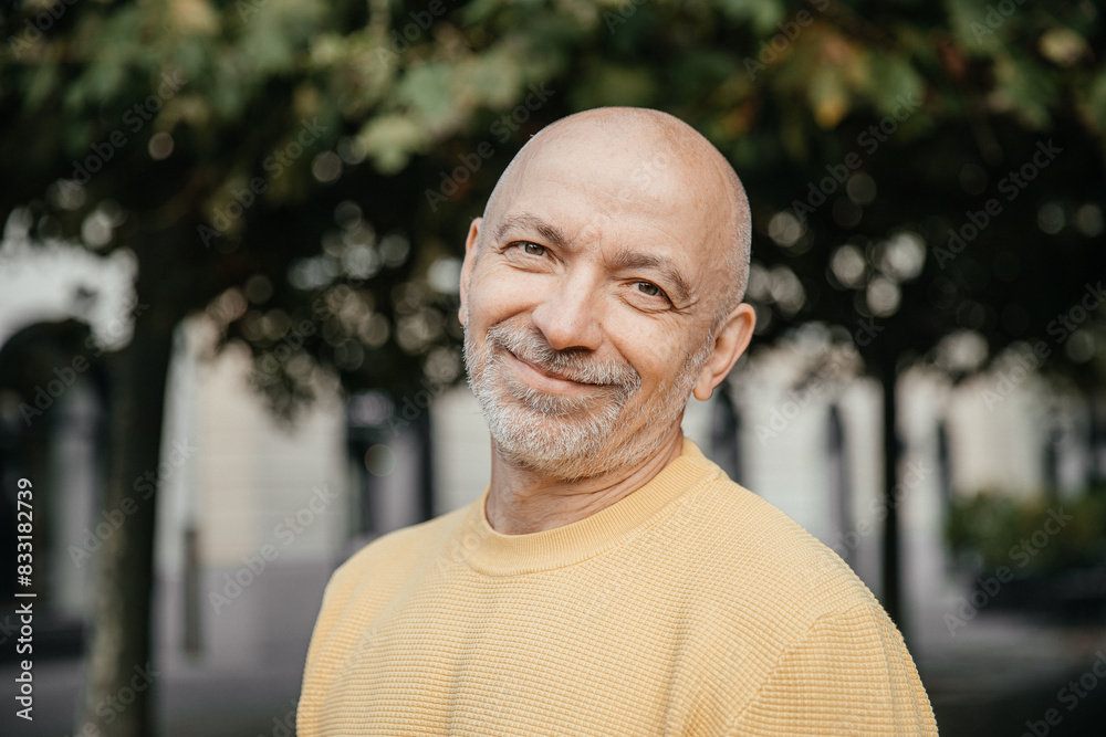 Senior Man in Yellow Sweater Smiling Gently in a Urban Setting Senior Man in Yellow Sweater Smiling Gently in a Urban Setting