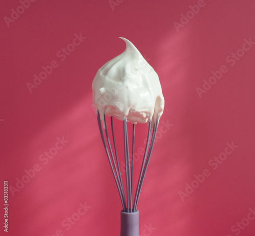whipped meringue on a whist on a pink background photo