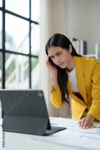 Stressed Asian woman Headache and fatigue from working long hours with a laptop in the office Office syndrome concept. © Phimwilai