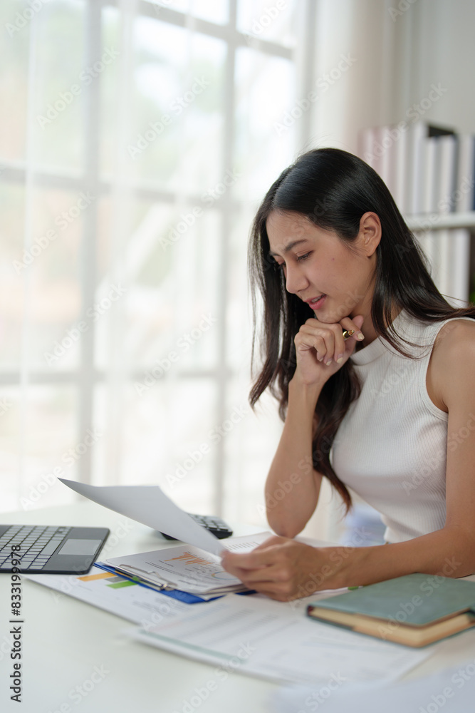 Confident businesswoman working with laptop and documents in home office, thinking, analyzing work happily. Confident businesswoman working with laptop and documents in home office, thinking, analyzing work happily.