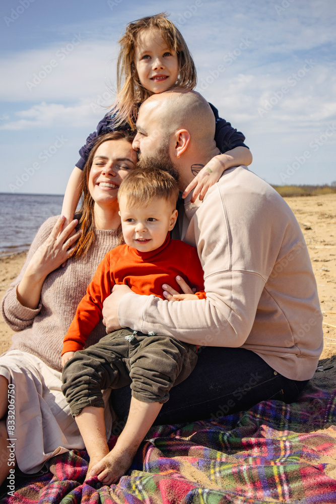 Portrait of loving family of parents and daughter with son on beach by sea Portrait of loving family of parents and daughter with son on beach by sea