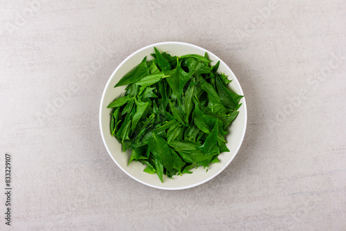 fresh green spinach leaves in a grey plate on a grey background top view