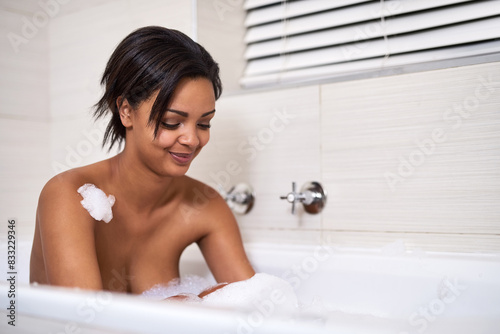 Bubble  bath and woman in bathroom for cleaning  washing or beauty at home in the morning. Soap  happy girl or relax in tub water for skincare cosmetic  wellness or foam for healthy hygiene in liquid